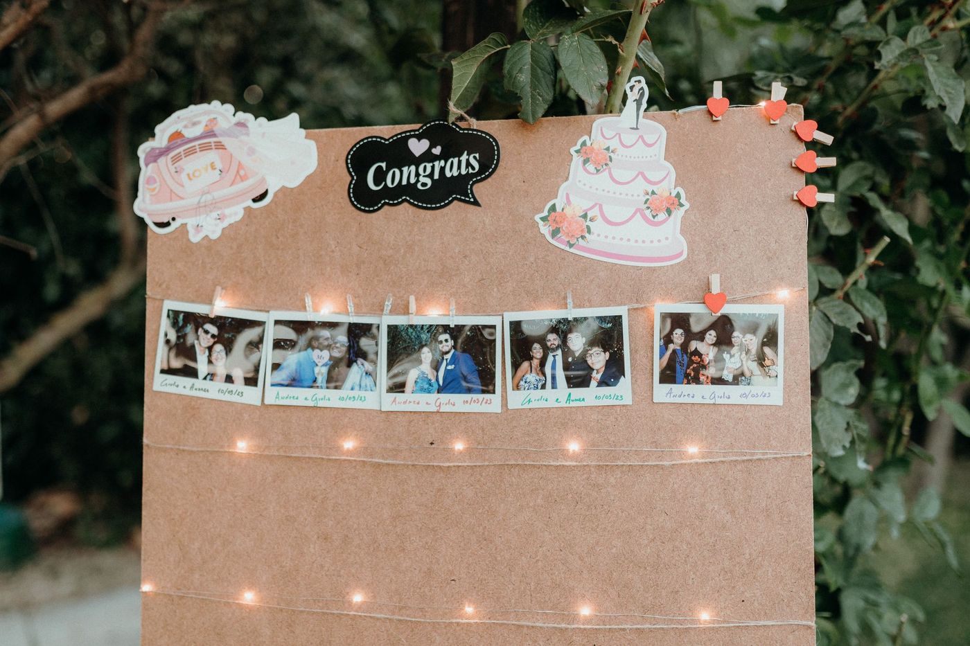 Bacheca con polaroid degli invitati e scritta Congrats